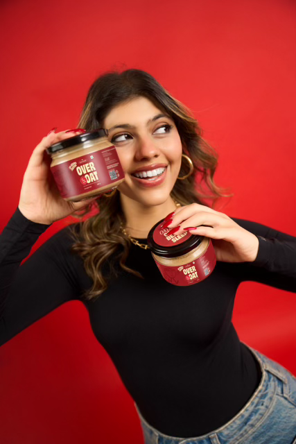 Aanch, founder of Over and Oat, holding two jars of overnight oats